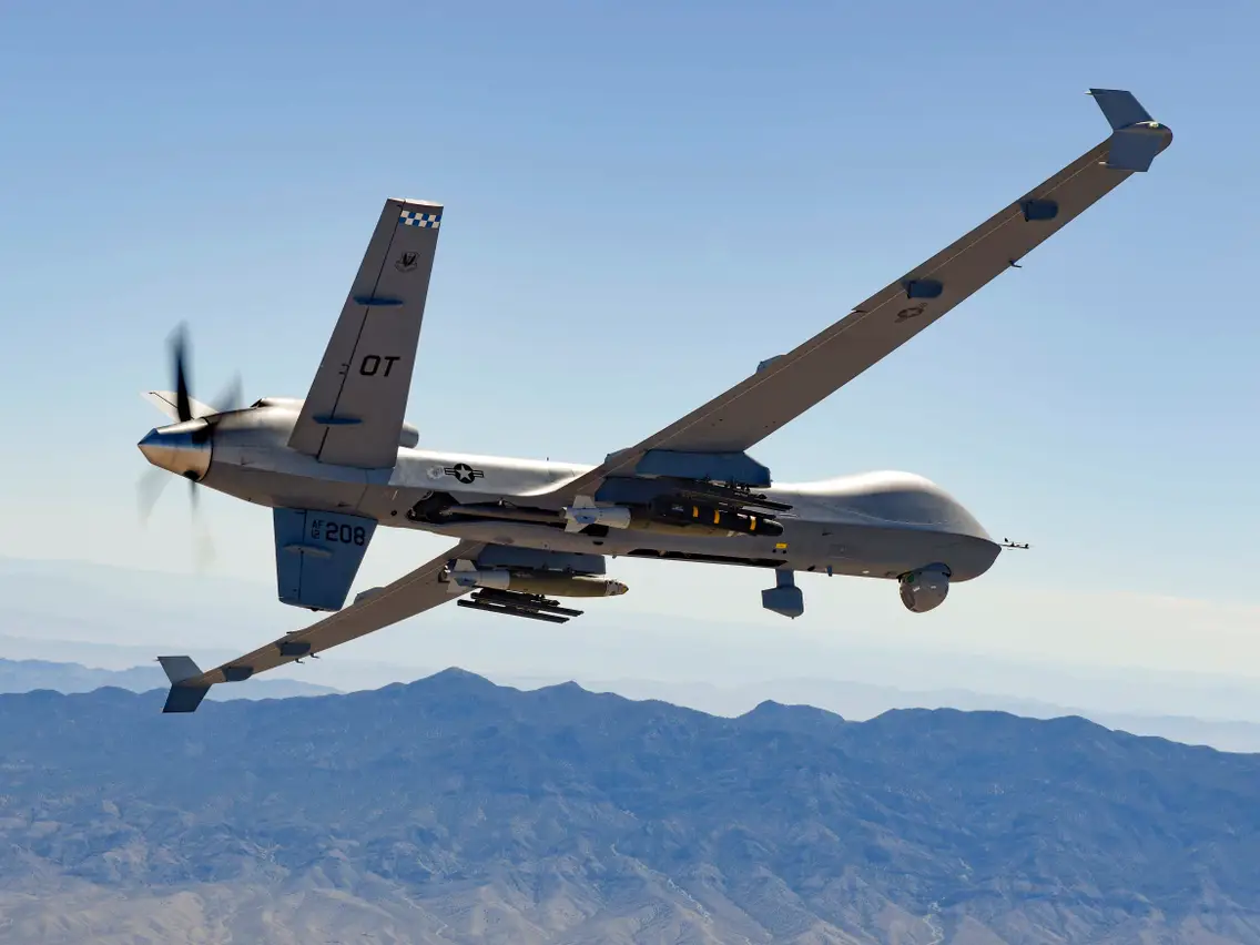 A military aircraft flying in the sky over mountains.