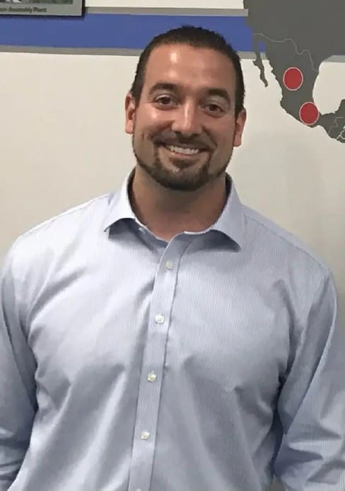 A man in a blue shirt smiling for the camera.