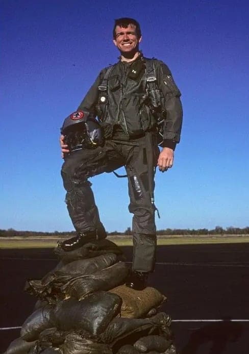 A man in black jacket standing on top of rock.