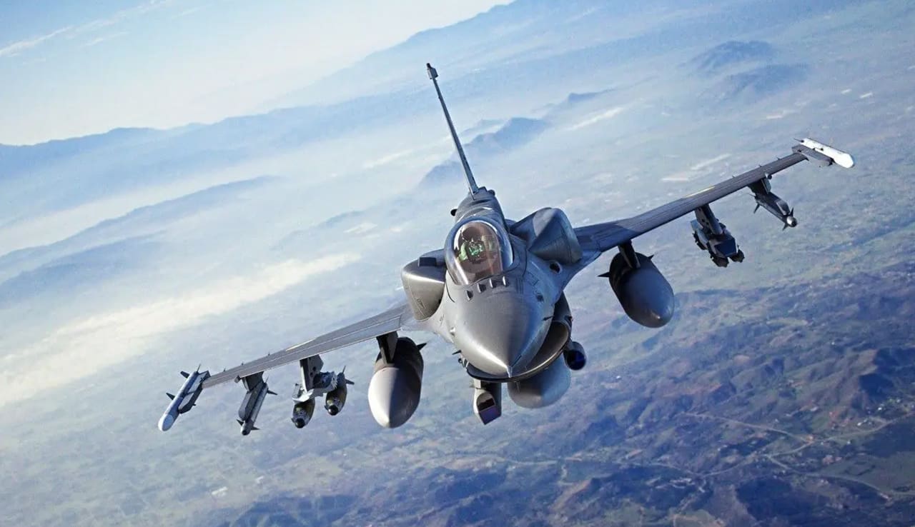 A fighter jet flying through the air over mountains.